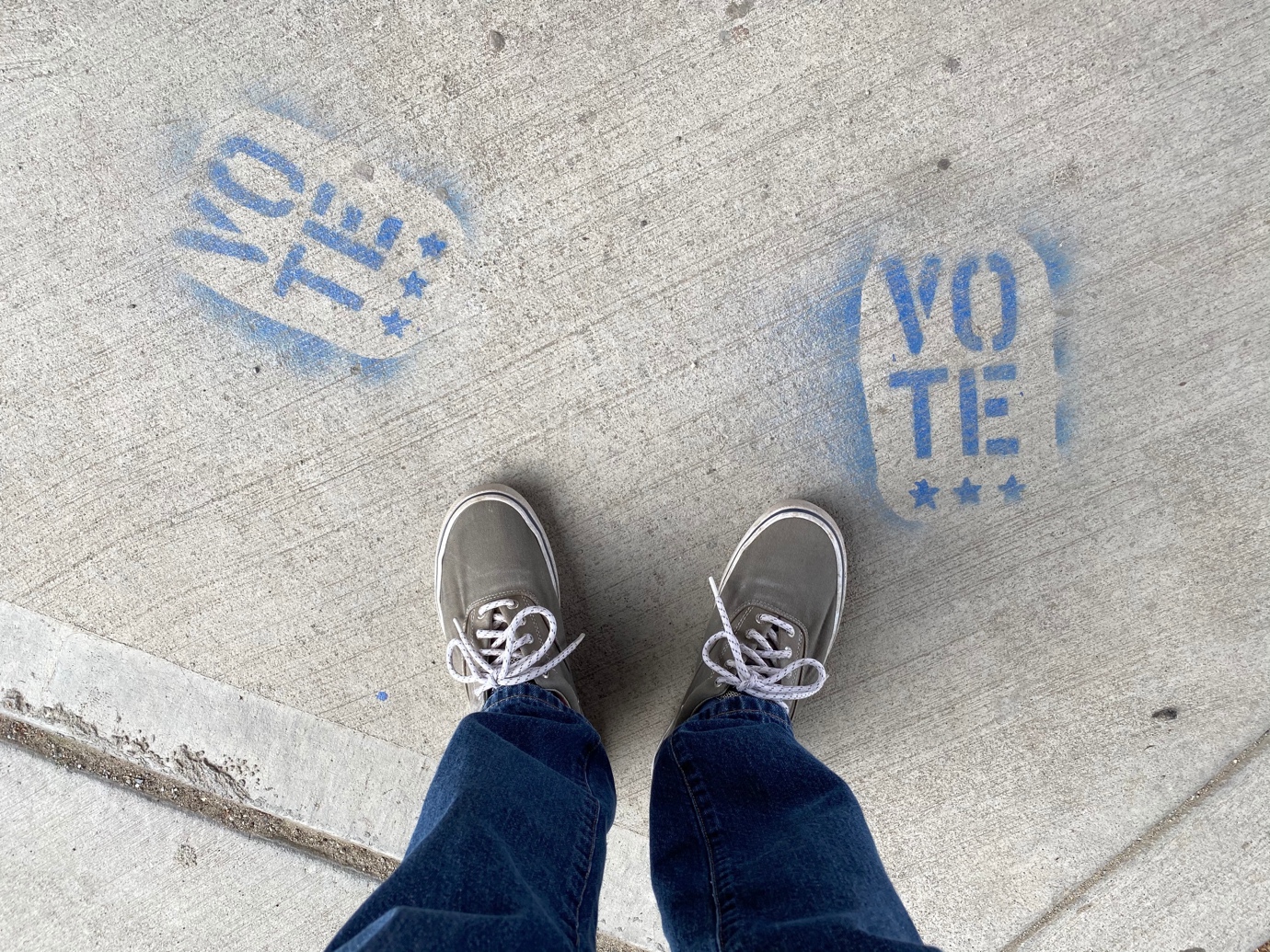 A person's feet and shoes on a sidewalk with blue painted footprints

Description automatically generated