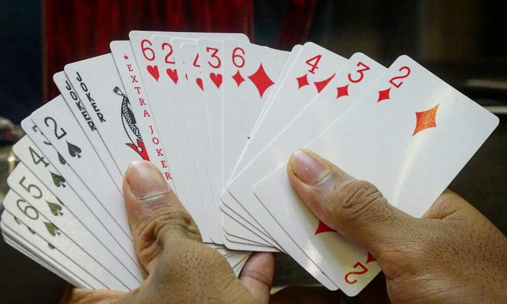 A hand holding a deck of cards Description automatically generated
