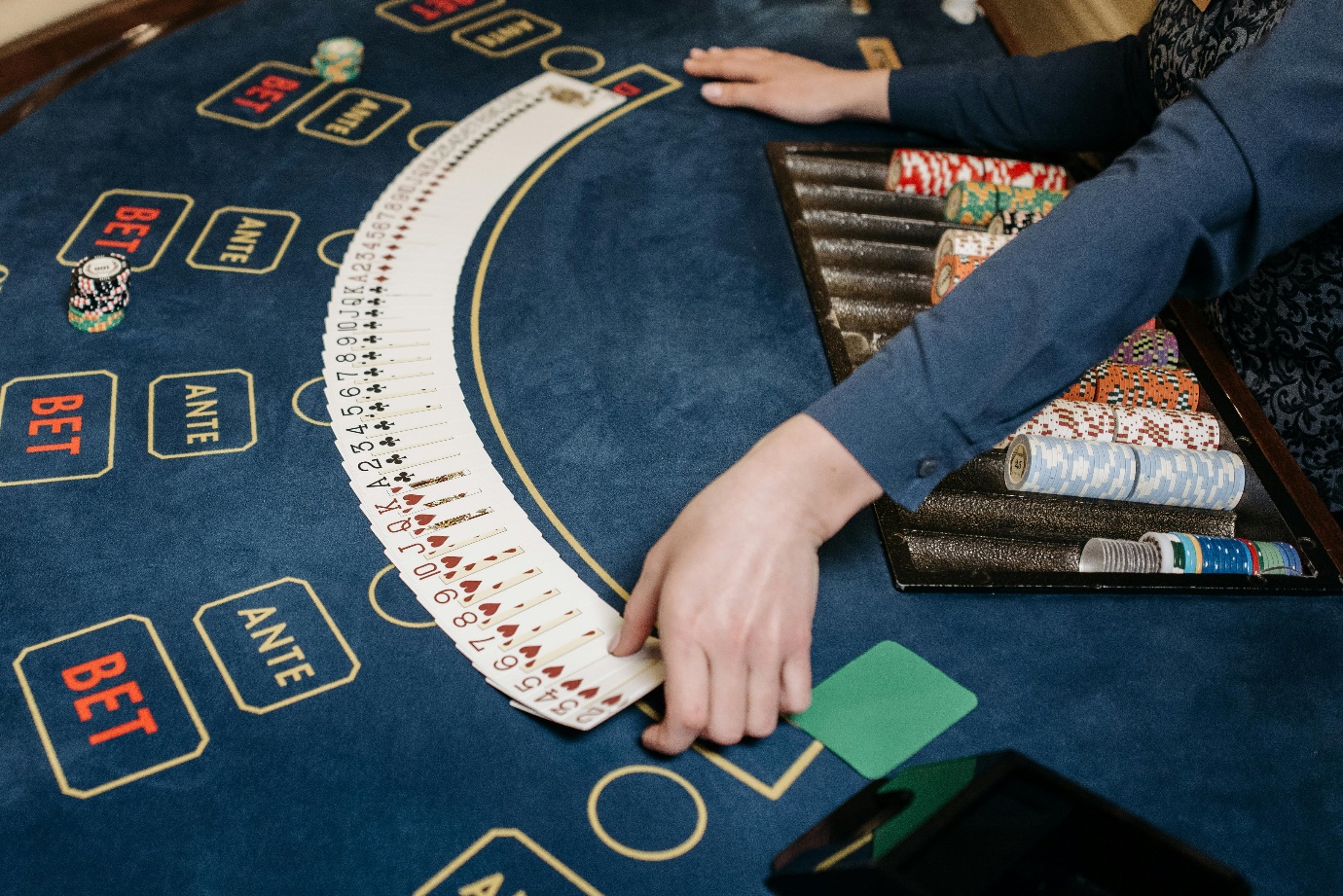 A person placing cards on a poker table

Description automatically generated